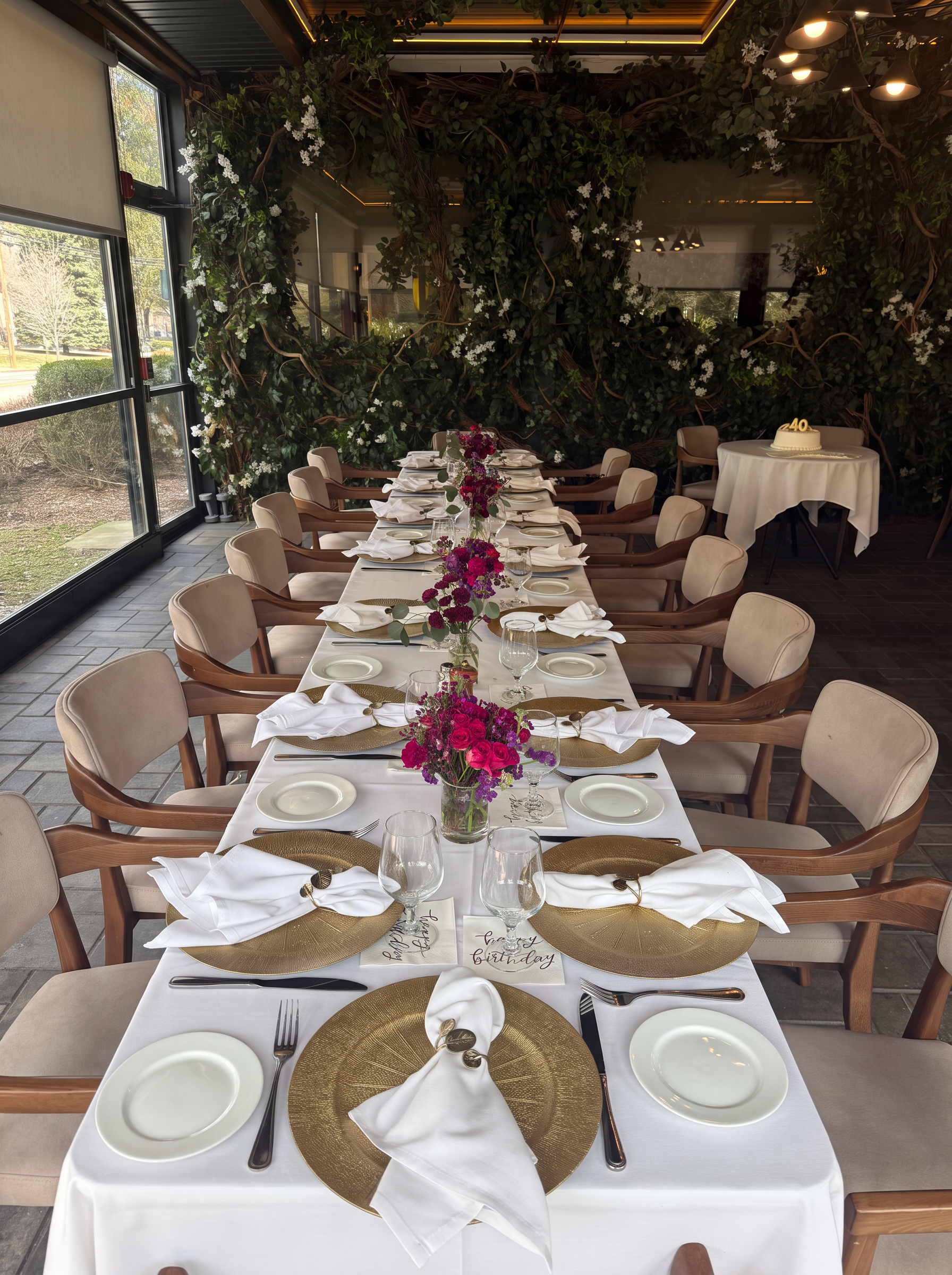 Elegant long table set for a social gathering with vibrant florals and gold chargers