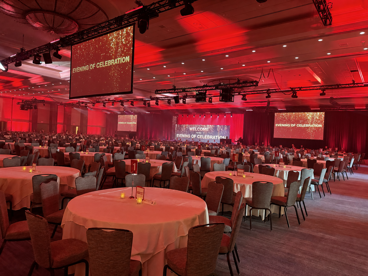Corporate awards dinner setup with round table, stage, podium and large screens in a ballroom